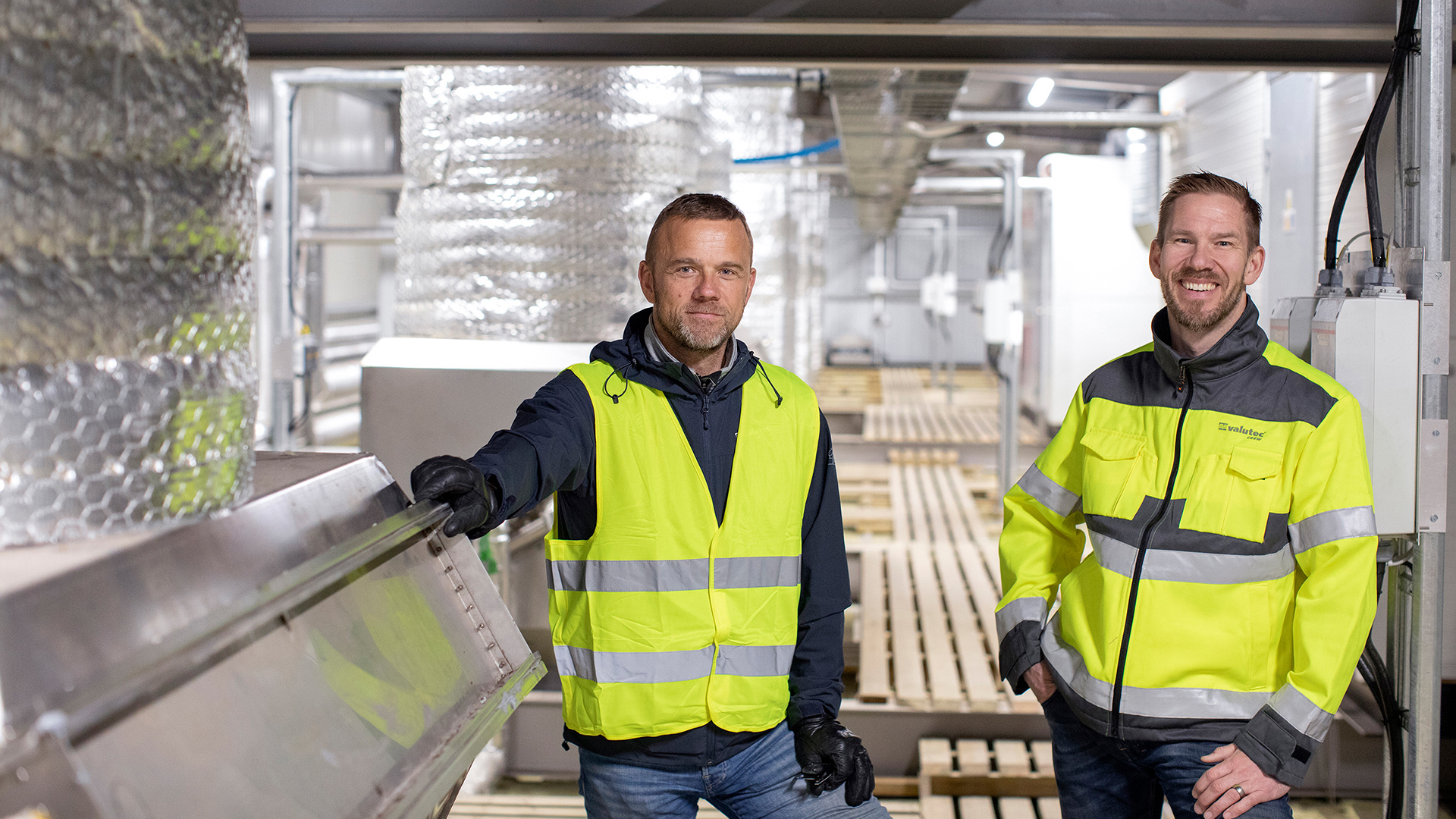 Two Valutec employees in high-visibility clothing inside a timber kiln.
